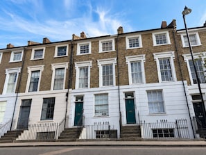 A row of terraced houses with white and brown brick facades, white window frames, and black metal railings. - Islington Gem Studio near Angel and Highbury (London)