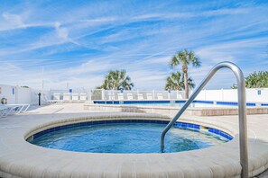 A swimming pool with a curved edge, a metal ladder, and lounge chairs. - Sandcastle North 302| 3br/2ba beach view (Indian Rocks Beach)