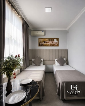 A hotel room with two beds, a dining table, and a painting on the wall. - Ulubey Hotel (Baku)