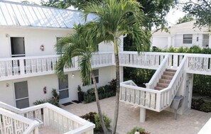Ein mehrstöckiges Gebäude mit weißer Fassade, einer zentralen Treppe und einer Palme.