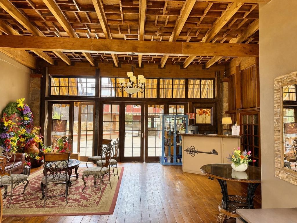 A room with a wooden ceiling, large windows, a reception desk, and a fireplace.