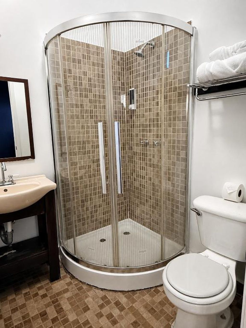 A corner bathroom with a glass-enclosed shower, a sink, and a toilet.