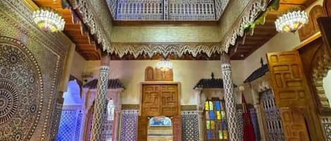 An ornate interior with intricate patterns, a balcony, and a chandelier.