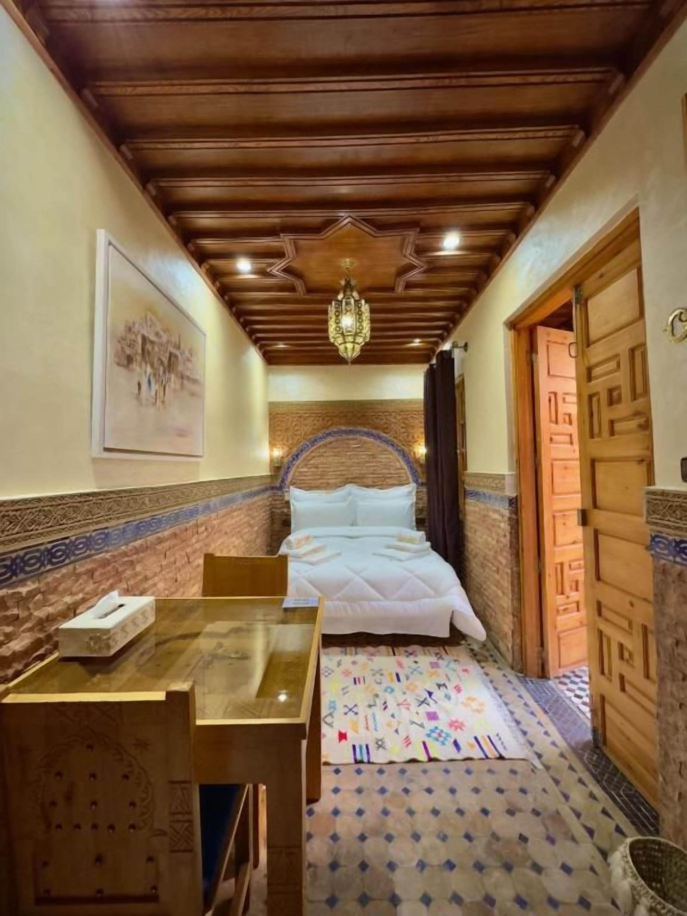 Een kamer met een bed, een tafel en een kamerbreed tapijt.