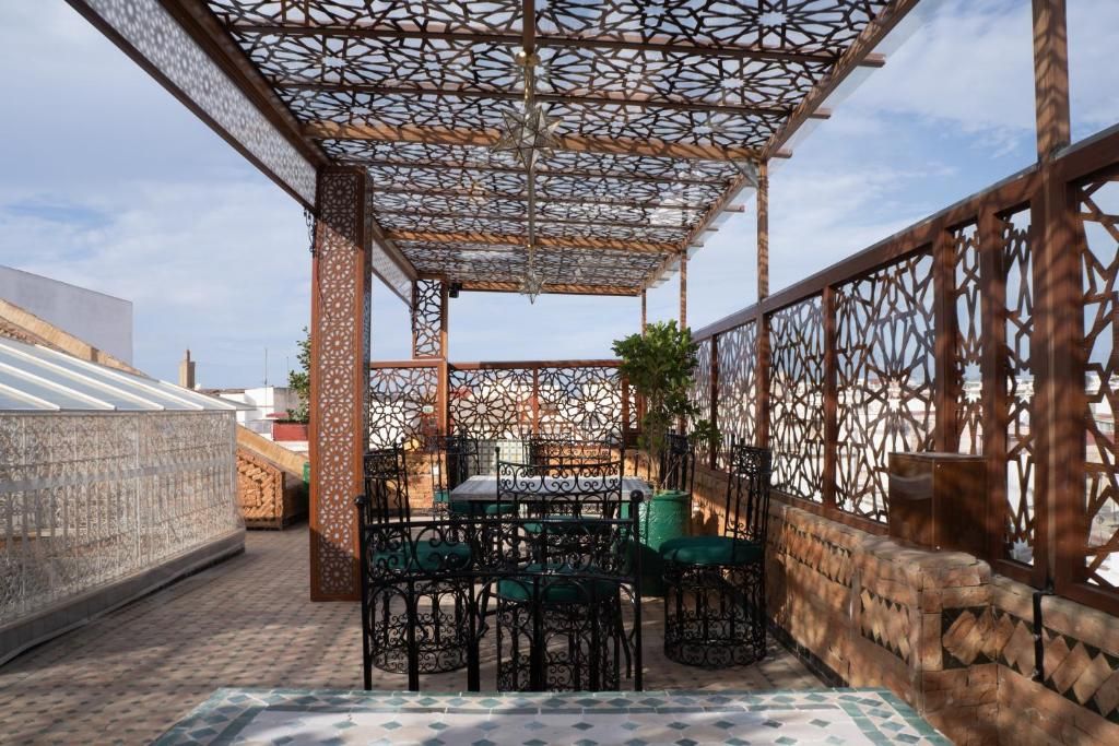 A rooftop terrace with a patterned ceiling, outdoor seating, and a view of the cityscape.