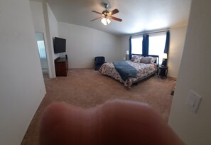 A bedroom with a bed, a ceiling fan, a TV, and a window with curtains. - Brilliant 3-bedroom house with AC, "The Oasis of Clarkdale" (Clarkdale)