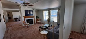 A living room with a fireplace, a sofa, a coffee table, and a ceiling fan. - Brilliant 3-bedroom house with AC, "The Oasis of Clarkdale" (Clarkdale)