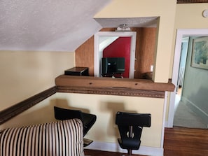 A staircase with a wooden handrail, a striped chair, and a black office chair. - Cozy 1-bedroom apartment in peaceful Grand Rapids with AC, walk to concerts. (Grand Rapids)