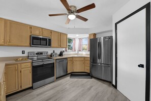 Eine moderne Küche mit Holzschränken, Edelstahlgeräten und einem Deckenventilator.