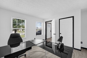 A conference room with a glass table, two chairs, and a door leading to another room. - 4-Bedroom House with Private Office in Canal Winchester (Canal Winchester)