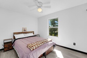 A bedroom with a bed, a nightstand, a ceiling fan, a window, and a wall socket. - 4-Bedroom House with Private Office in Canal Winchester (Canal Winchester)