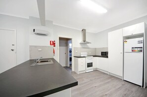 A modern kitchen with a central island, built-in oven, microwave, and white cabinetry. - Hook, Wine & Linger on Learmonth (Portland)