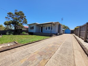 A residential property with a paved driveway, a house with a front porch, and a small backyard with a tree. - Hook, Wine & Linger on Learmonth (Portland)