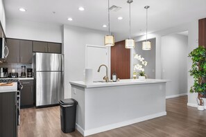 Eine moderne Küche mit Edelstahl-Kühlschrank, einer Spüle und Pendelleuchten.