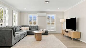 A modern living room with a sectional sofa, a round coffee table, and a TV on a wooden stand.