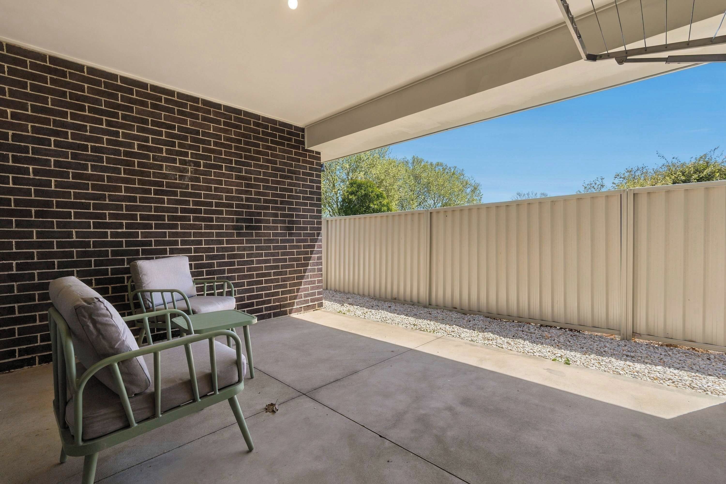 A patio with a brick wall, a metal table, and two chairs.