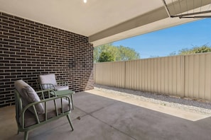 A patio with a brick wall, a metal table, and two chairs. - Morrisset Retreat - Sleeps 5, Walk to Bathurst CBD (Bathurst)