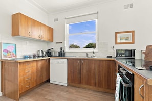 A modern kitchen with wooden cabinets, a dishwasher, a window with a view, and a microwave. - Bathurst Family Home - 3 Bed, Sleeps 6, Near Mount Panorama (Bathurst)