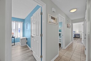 A hallway with a blue accent wall, white doors, and a sign that reads 'LIFE is good at the BEACH'. - Oceanview Condo - Huge Deck Overlooking Ocean with Pool! (Carolina Beach)