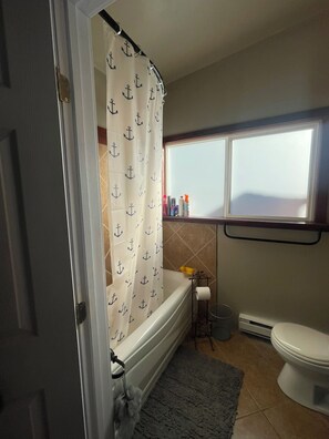 A bathroom with a bathtub, toilet, and a window. - The Captain at Secret Bay Hideaway (Private Oceanfront Cottage with Moorage) (Egmont)