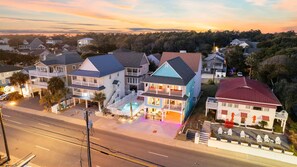 A residential area with houses featuring balconies, a swimming pool, and a red-roofed building. - A Little Piece of Heaven - Colorful 5BR w/ Ocean-View Porches & Shared Pool (Walk to Beach) (North Myrtle Beach)