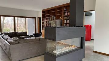 Un salon moderne avec une cheminée, un canapé d’angle et une bibliothèque.