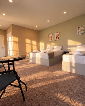 Habitación de hotel con dos camas, una mesa redonda y una silla.