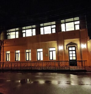 Edifício com várias janelas e entrada protegida por grades à noite.
