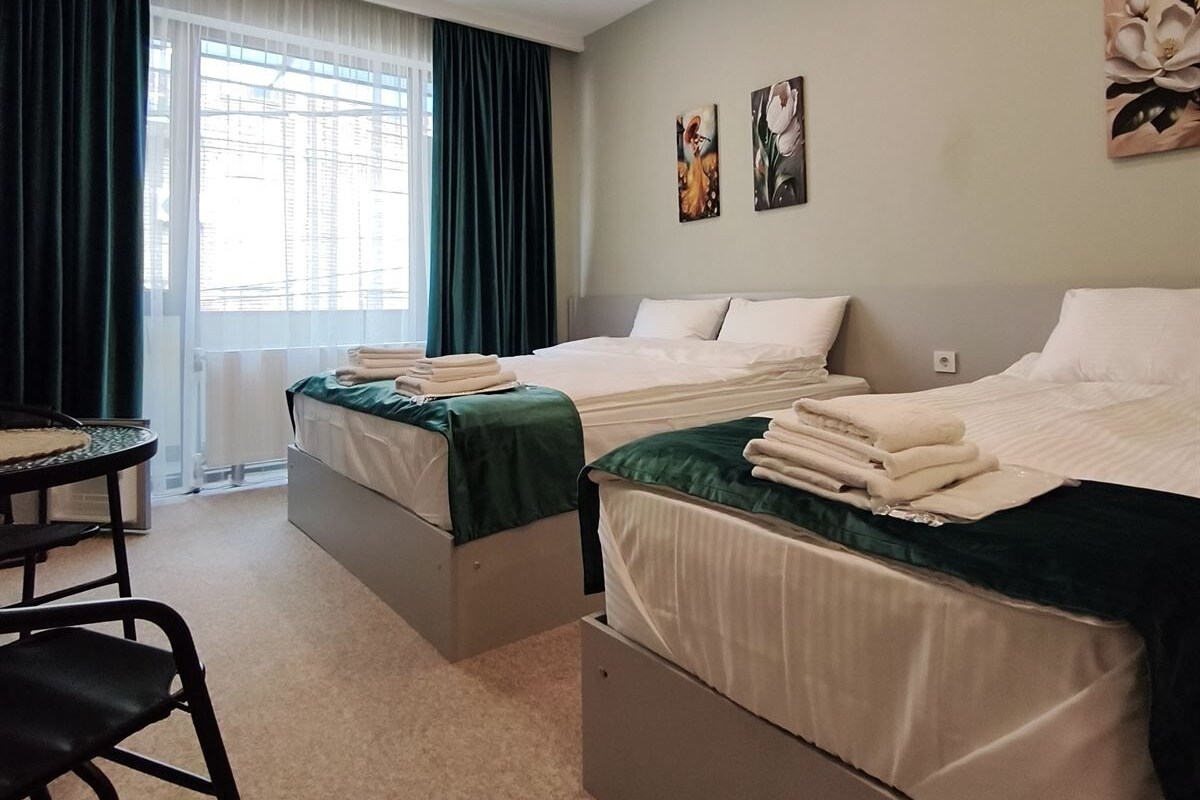 Quarto de hotel com duas camas, uma escrivaninha e uma cadeira.