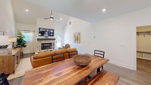 A modern living room with a wooden dining table, leather sofa, and a fireplace.