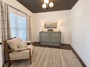 A room with a wooden chair, a grey cabinet, a patterned rug, and a ceiling light fixture.