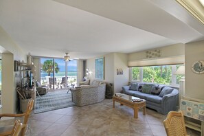 A spacious living area with a view of the ocean, a balcony with outdoor furniture, and a ceiling fan. - Enjoy stunning Gulf views from this beachfront Sanibel condo - Lighthouse Point 223 (Sanibel Island)