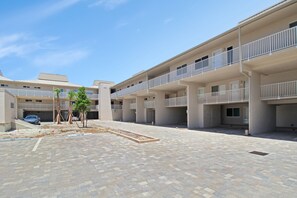 A multi-story building with balconies and a paved courtyard. - Enjoy stunning Gulf views from this beachfront Sanibel condo - Lighthouse Point 223 (Sanibel Island)