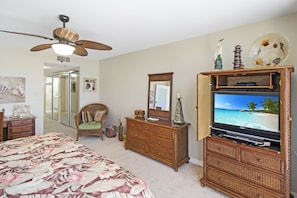 A bedroom with a bed, a dresser, a television, and a ceiling fan. - Enjoy stunning Gulf views from this beachfront Sanibel condo - Lighthouse Point 223 (Sanibel Island)