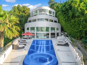 A modern multi-story building with a swimming pool, outdoor seating, and a staircase leading to the entrance. - Mulholland Ridge By Alora Reserve (Los Angeles)