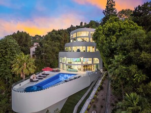 A multi-story modern building with a pool and outdoor seating, surrounded by lush greenery. - Mulholland Ridge By Alora Reserve (Los Angeles)