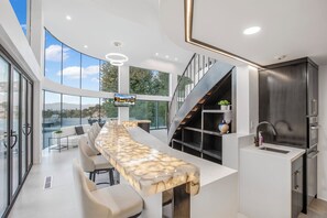 A modern kitchen with a long island, built-in appliances, and a view of the outdoors. - Mulholland Ridge By Alora Reserve (Los Angeles)