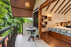 Ein Balkon mit Tisch und Stühlen, ein Bett mit gemustertem Überwurf und eine hängende Leuchte.