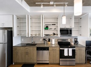A modern kitchen with built-in appliances, open shelving, and a dining area. - Chic 2BR Near UAB & Dining 86 (Birmingham)