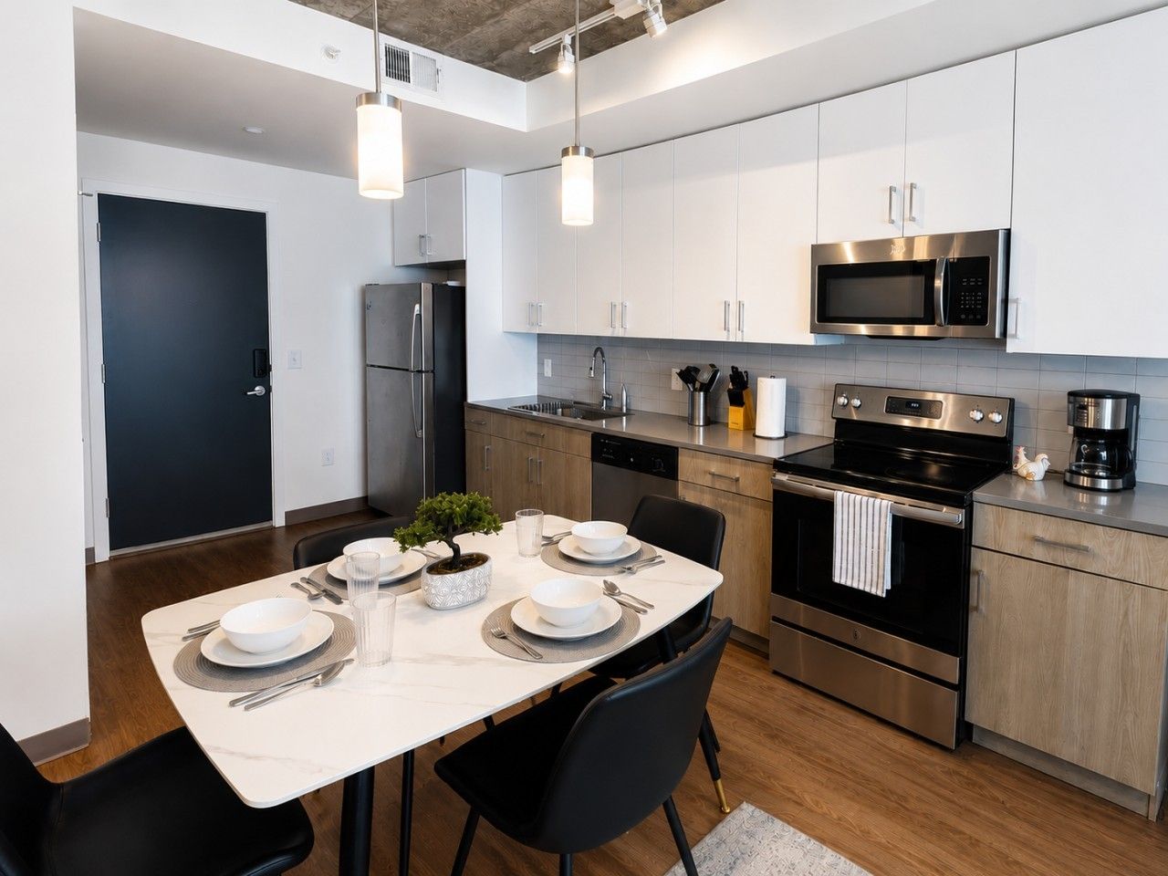A modern kitchen with white cabinets, stainless steel appliances, and a dining area with a table set for four.