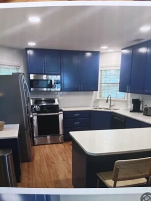A compact kitchen with dark blue cabinets, a stainless steel refrigerator, a microwave, and a sink. - Updated 1-bedroom condo, less than a mile from Stadium, LG covered outdoor space (Oxford)