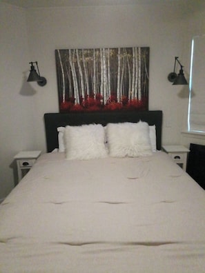 A bed with white bedding, a headboard with a forest-themed artwork, and two bedside lamps. - Updated 1-bedroom condo, less than a mile from Stadium, LG covered outdoor space (Oxford)