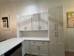 A kitchen with white cabinets, a dishwasher, and a countertop. - 3-bedroom house in tranquil Naples with cool AC breeze (Naples)