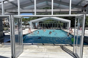 An outdoor swimming pool with a covered area, surrounded by a fence, and a clear sky above. - Marina, Year-Round Pool, Near Beach, Large Dining (South Haven)