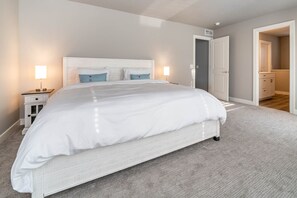 A bedroom with a large bed, bedside lamps, a nightstand, and a door leading to a bathroom. - Marina, Year-Round Pool, Near Beach, Large Dining (South Haven)