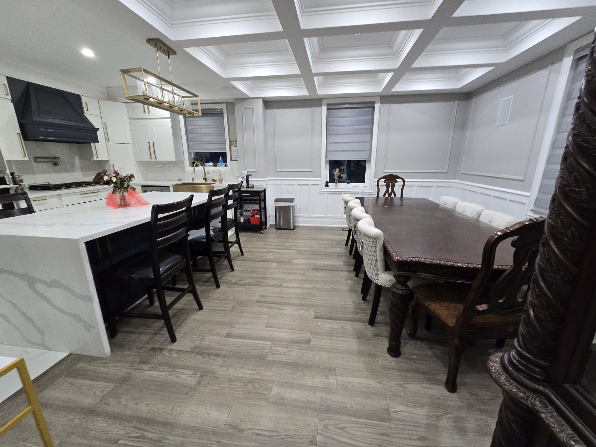 A modern kitchen with white cabinetry, a central island, and a dining area with a large table and chairs.