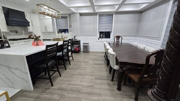 A modern kitchen with white cabinetry, a central island, and a dining area with a large table and chairs.