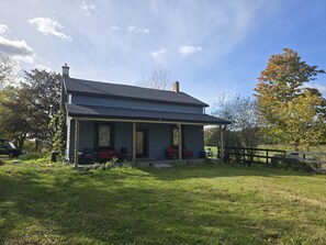 A two-story house with a porch, a chimney, and a fenced yard. - Country Farmhouse Retreat with Pool (Uxbridge)