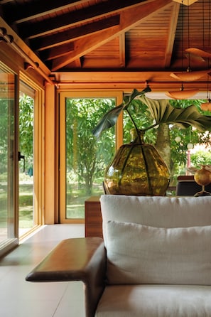 Ein modernes Interieur mit Holzboden, einem Glastisch und einer Couch mit einer Vase voller grüner Blätter.