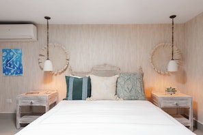 Ein Schlafzimmer mit einem großen Bett, zwei Nachttischen, einem Kopfteil mit dekorativem Muster und zwei Wandleuchten.